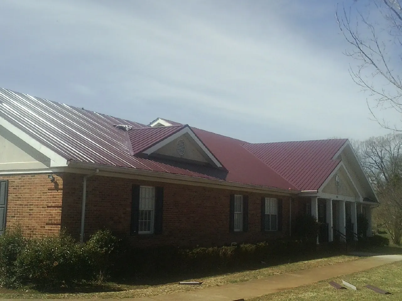 Red metal roof with gabled entries on a long brick building, from a Hail Damage Roof Repair job in Chicago Ridge