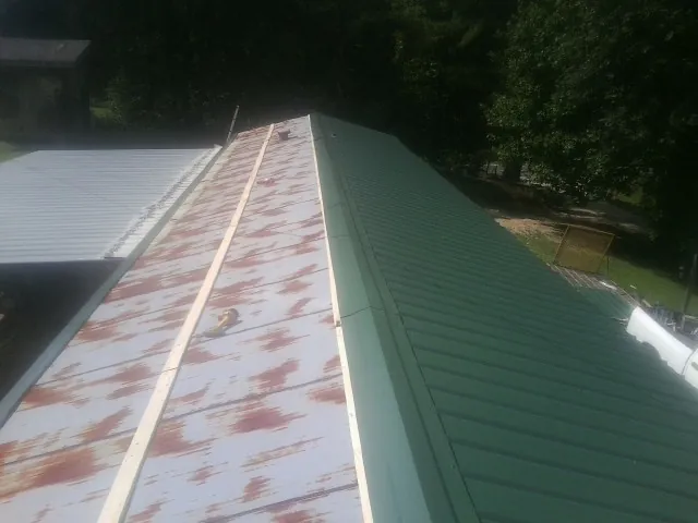 Old rusted panels beside newly installed green metal roofing — Wind Damage Roof Repair by Roofing Brothers in Chicago Ridge