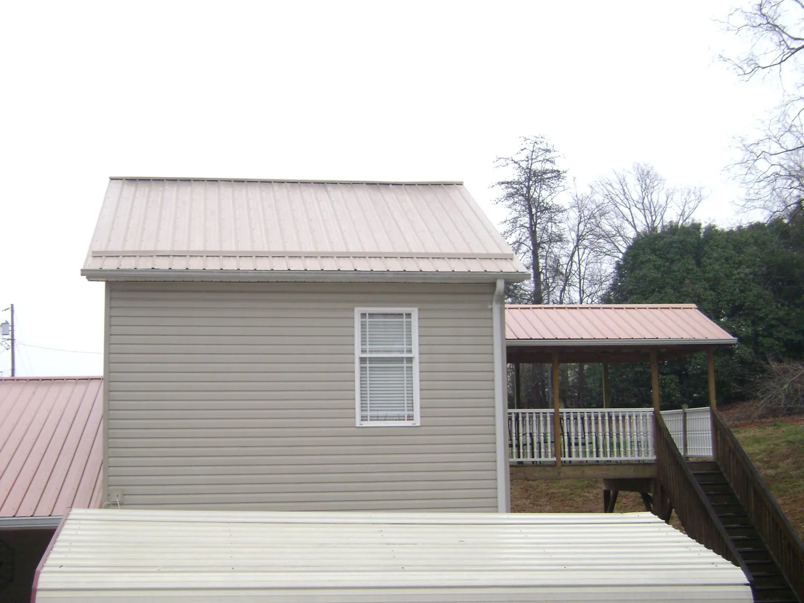 Tan metal roofs on a two story addition and attached porch, from a Roof Replacement job in Chicago Ridge